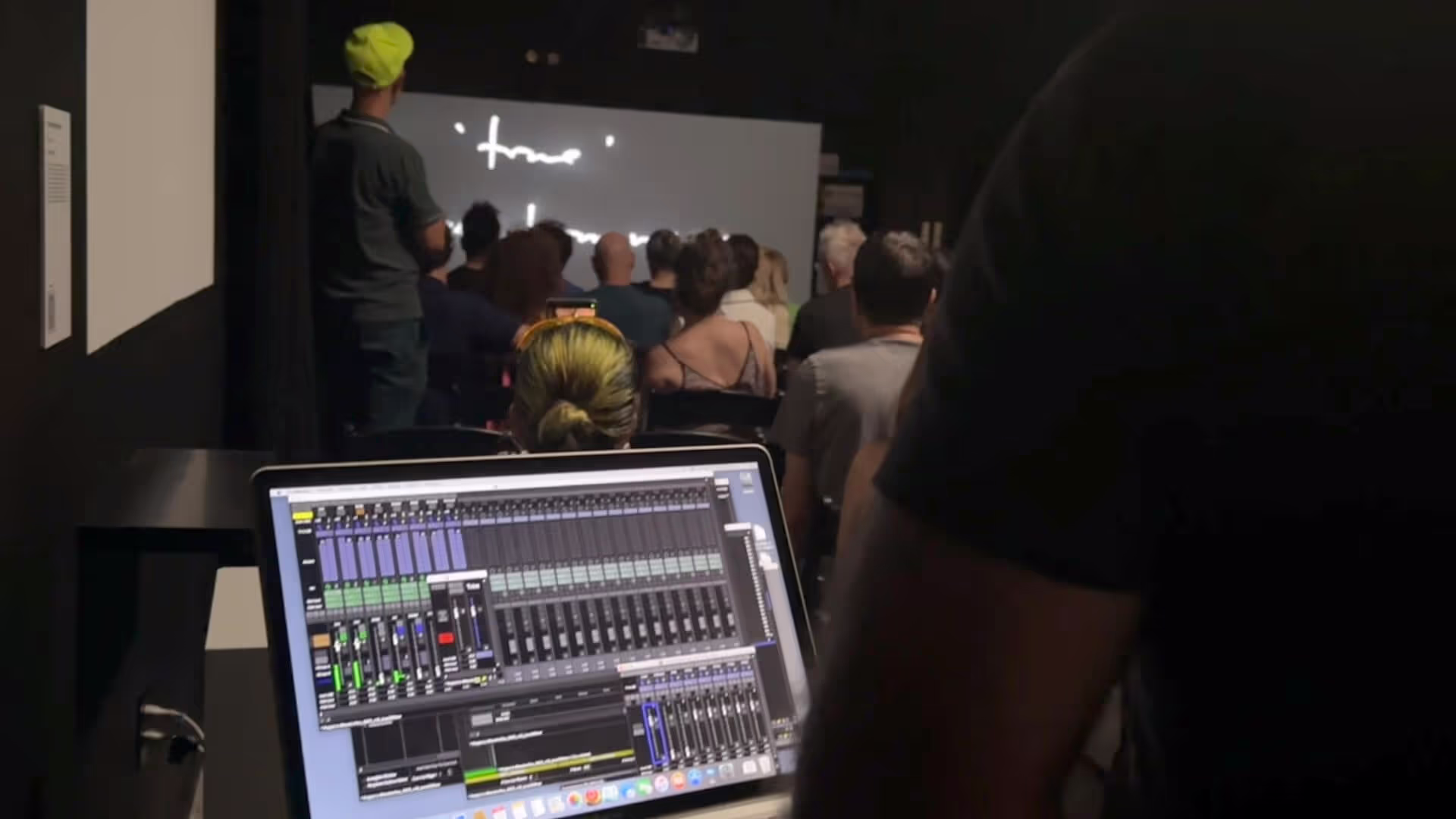 MUD Foundation The Sound of Art Experimental Music and Sound Art Program, featuring an audience seated in a dark room while a person operates audio mixing software on a laptop in the foreground.