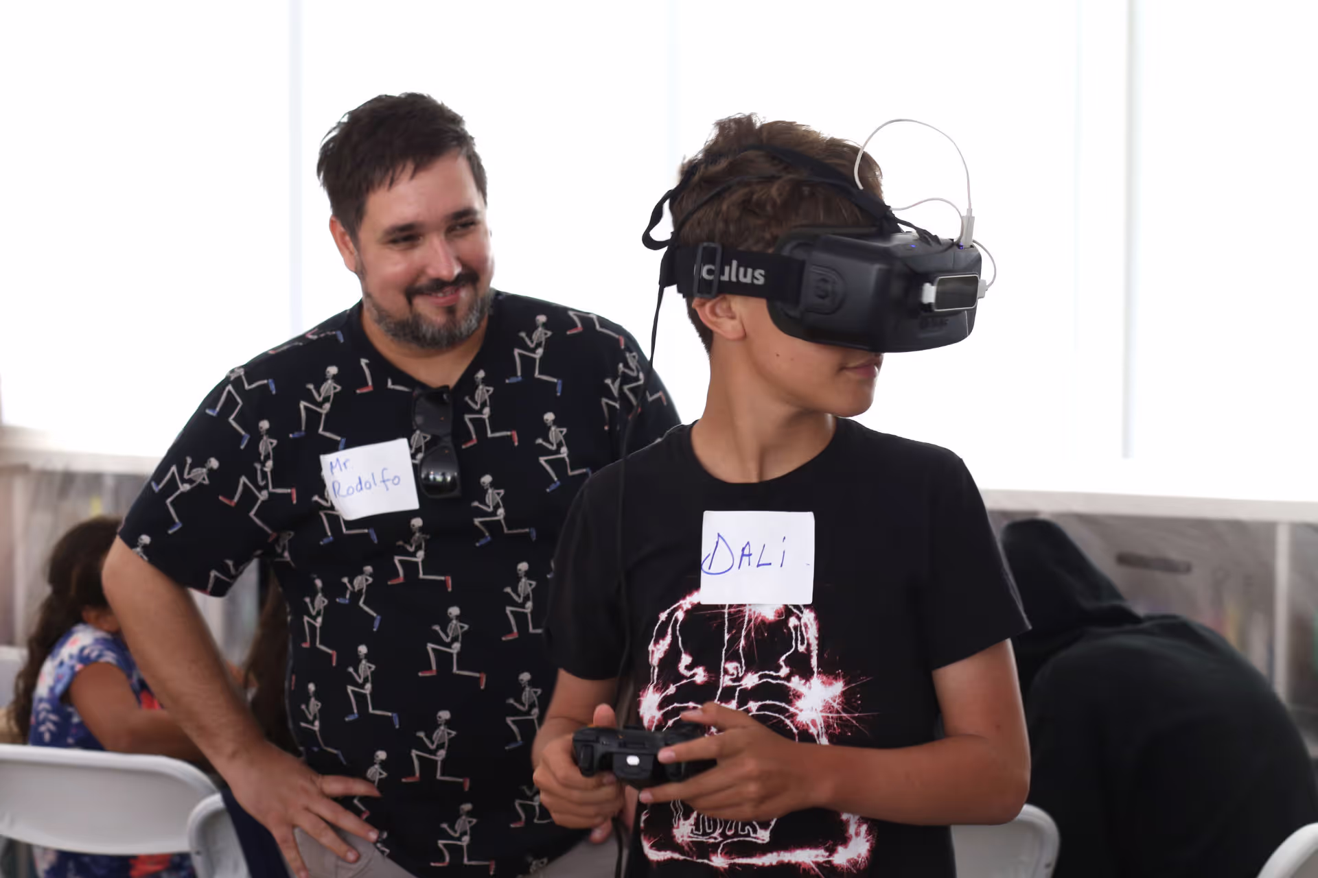 MUD Foundation XRCamp at the De La Cruz Collection in Miami, Florida, 2017, featuring a boy wearing an Oculus VR headset and holding a controller beside a smiling man, with name tags reading “DALI” and “Mr Rodolfo.”