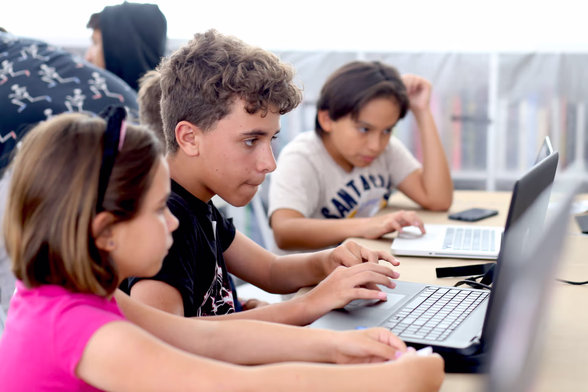 MUD Foundation XRCamp at the De La Cruz Collection in Miami, Florida, 2017, featuring three children working together on laptops at a table, including a girl in a pink shirt and two boys.