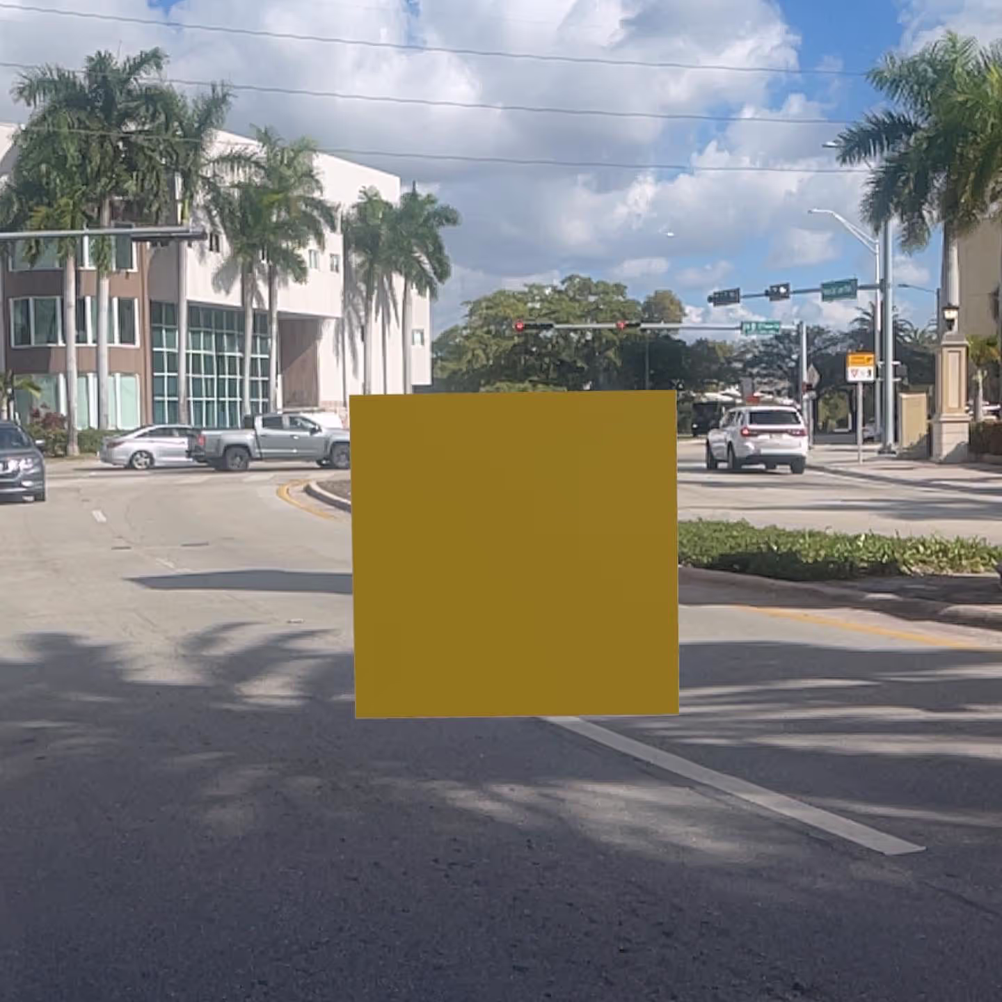 MUD Foundation Vuk Ćosić’s Yellow Pixel AR, featuring an urban street scene with palm trees, vehicles stopped at a red traffic light, and a partly cloudy sky.