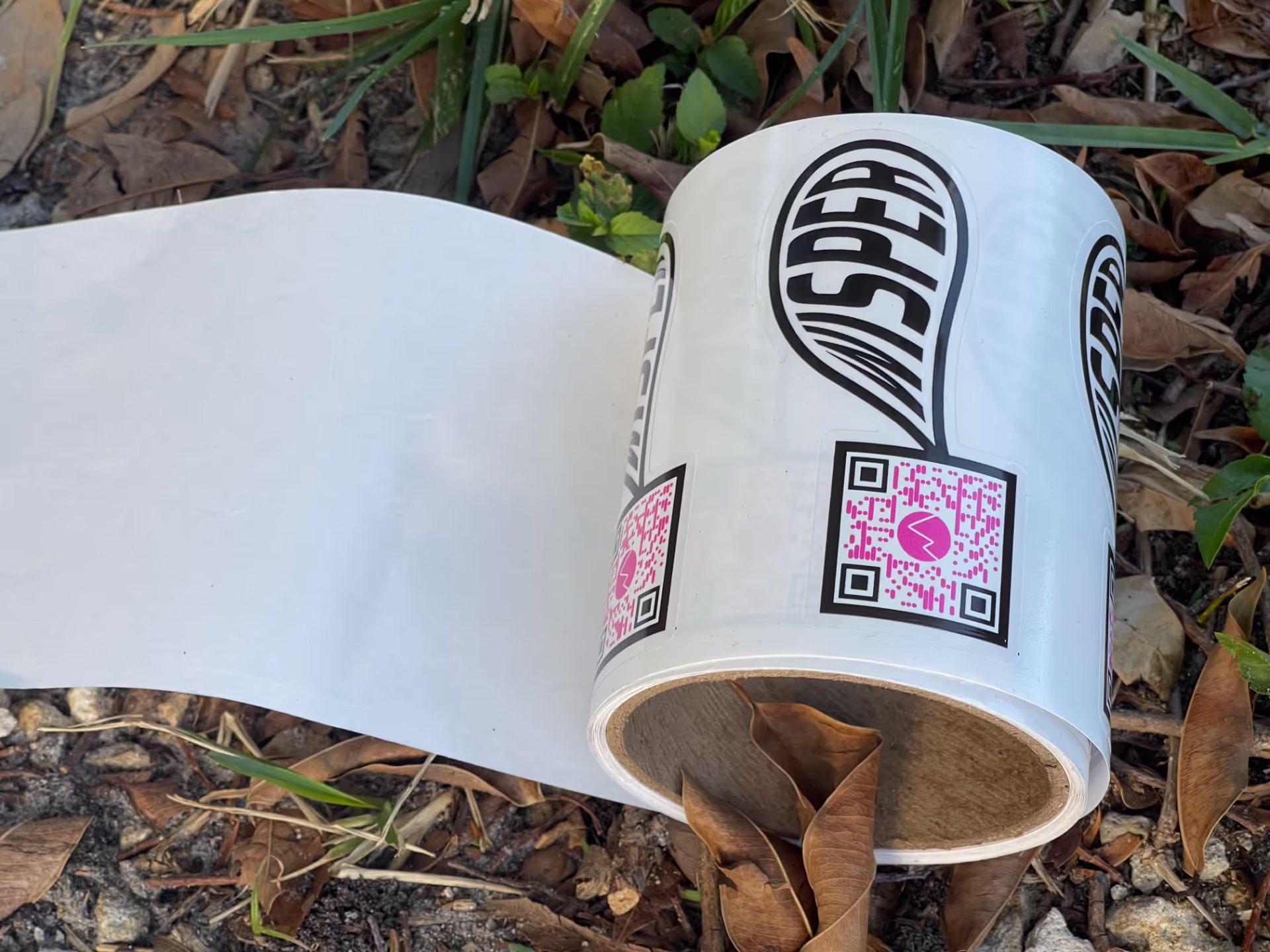 MUD Foundation WISper, featuring a roll of white labels on the ground among dried leaves and grass, each marked with the word “WISPER” inside a black balloon shape and a pink QR code.