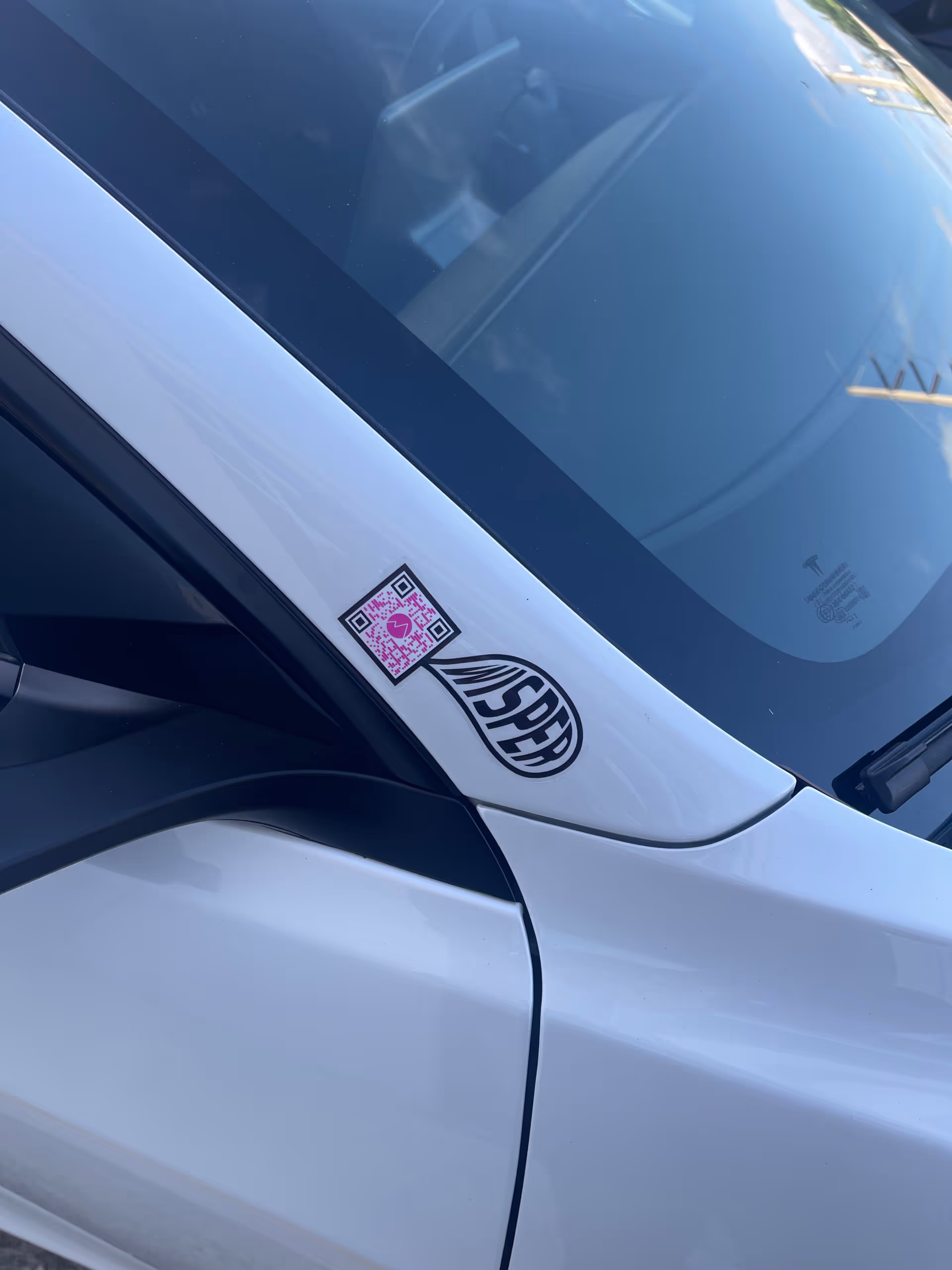 MUD Foundation WISper, featuring a close-up of a white car windshield with a black WISPER logo decal and a small pink-and-black QR code sticker near the side mirror.