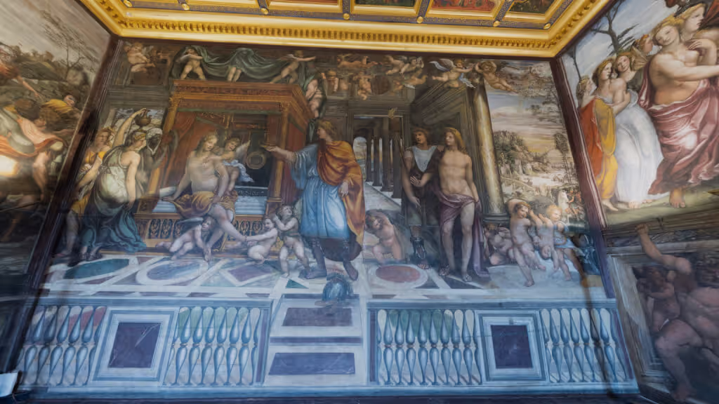 MUD Foundation Giulio Romano’s Bedroom of Agostino Chigi in Verse, featuring richly detailed Renaissance frescoes depicting classical figures, cherubs, and architectural elements, framed by elaborate painted borders and a decorated gold-trimmed ceiling.