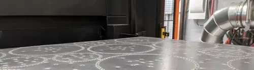 A laser cut metal sheet sits on the laser bed