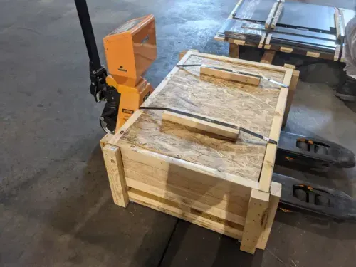 a close up of a forklift with a wooden crate filled with metal parts on it