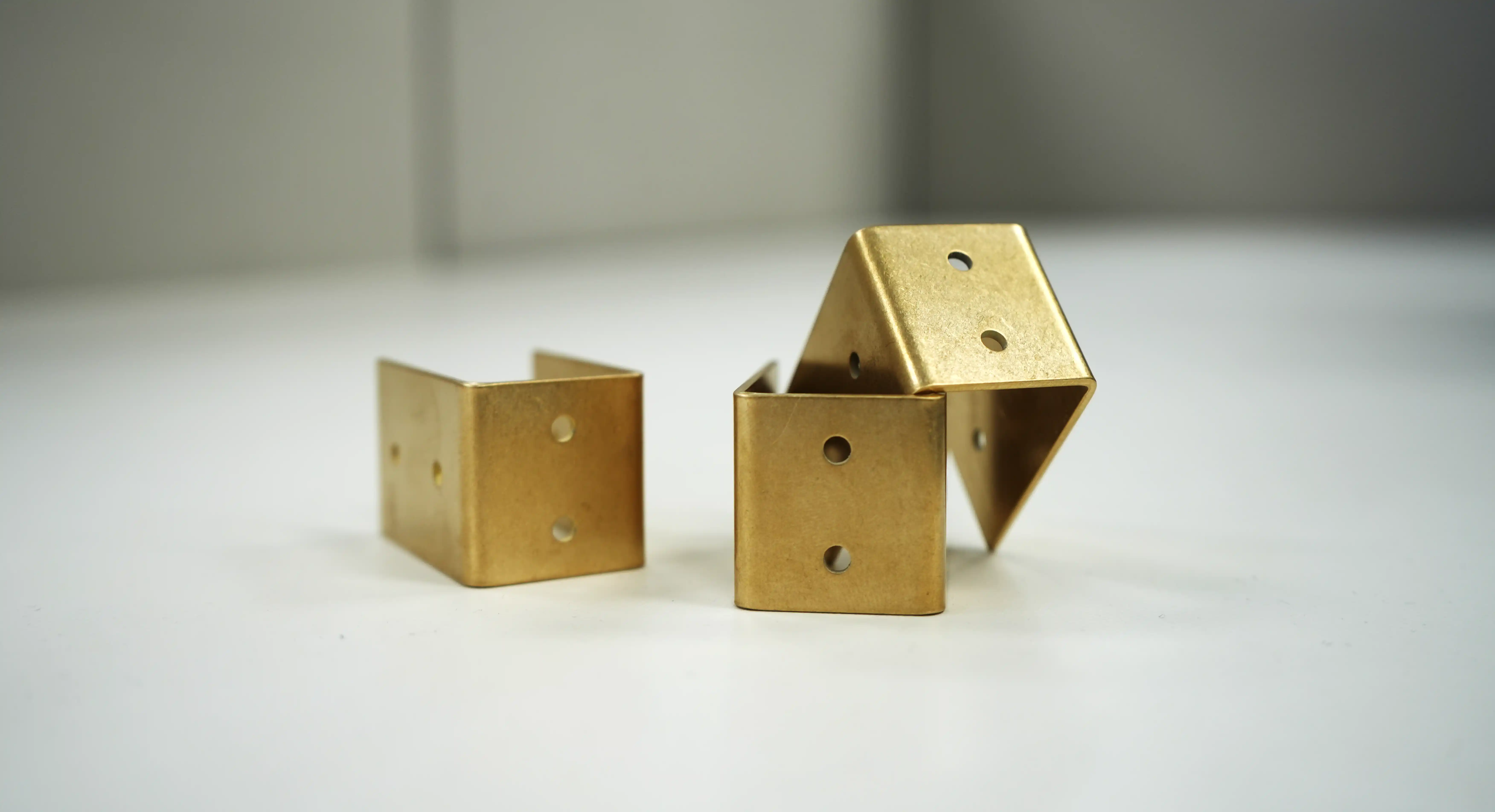 Three tumbled bent brackets with smooth, rounded edges
