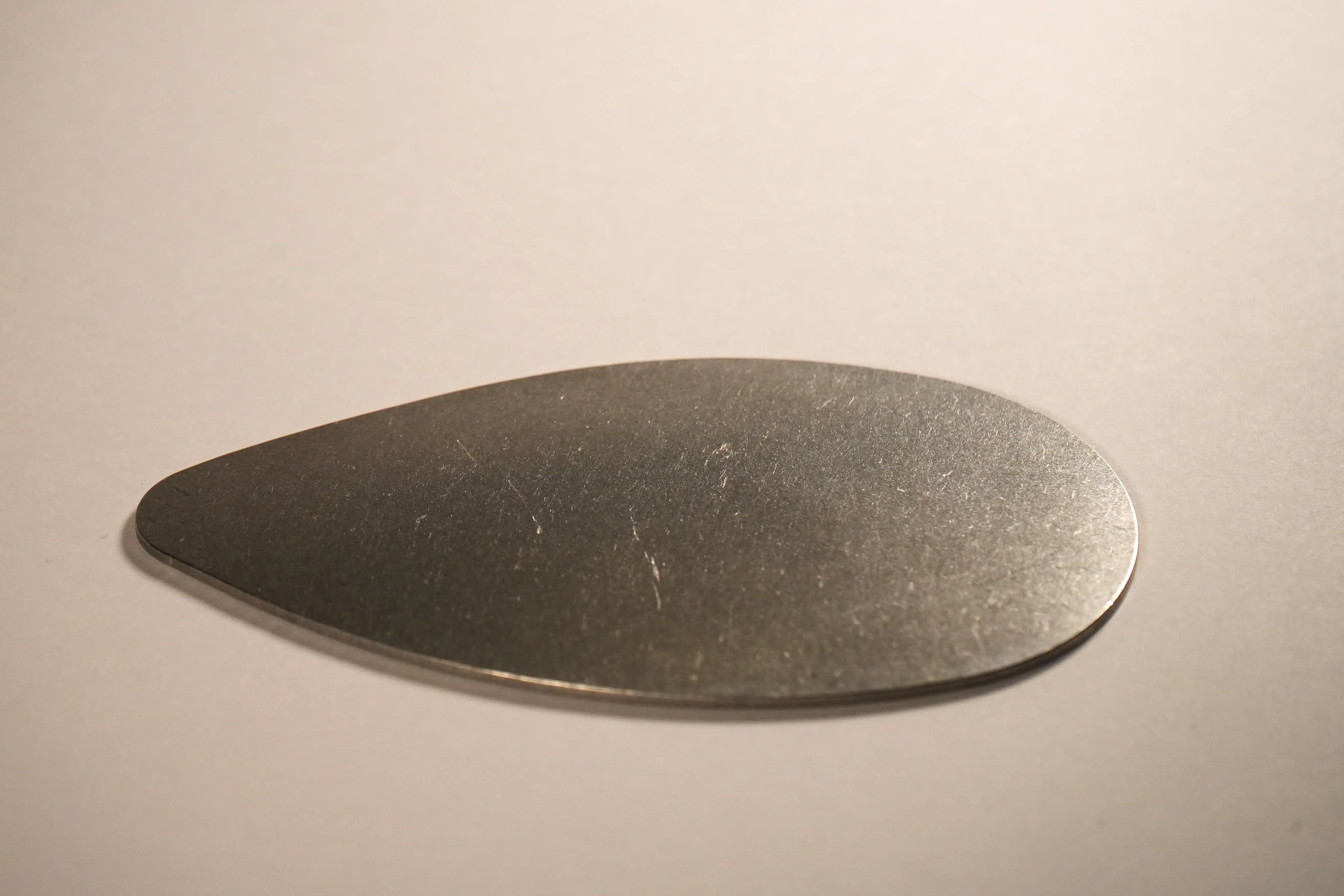Tumbled teardrop-shaped metal part with a satin finish
