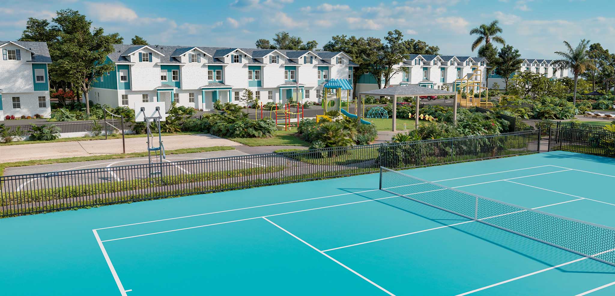 Blue tennis court with net in foreground, playground, houses, and greenery in background under a blue sky.