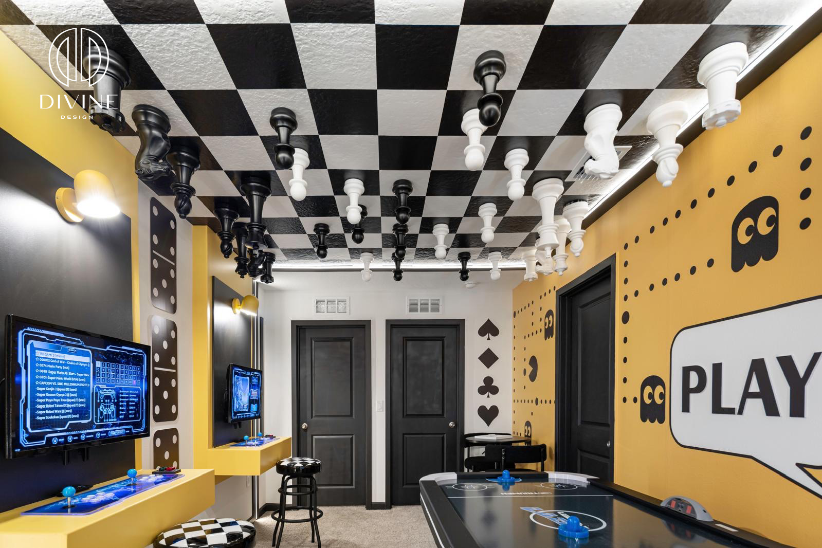 Game room with inverted chess pieces on ceiling, arcade game stations, yellow walls, and air hockey table.
