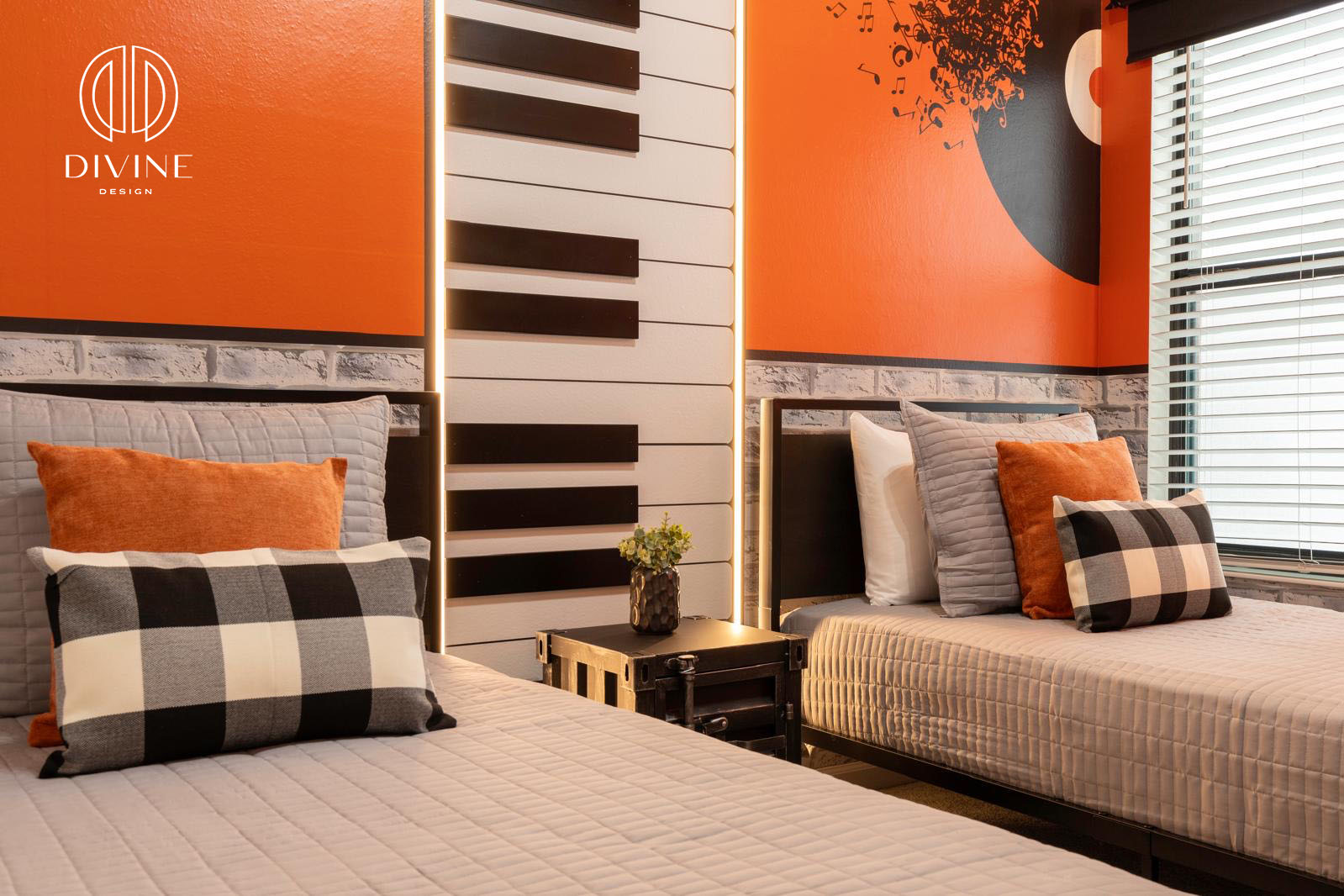 Twin beds with gray bedding and orange, plaid pillows in a music-themed room with piano key wall art.