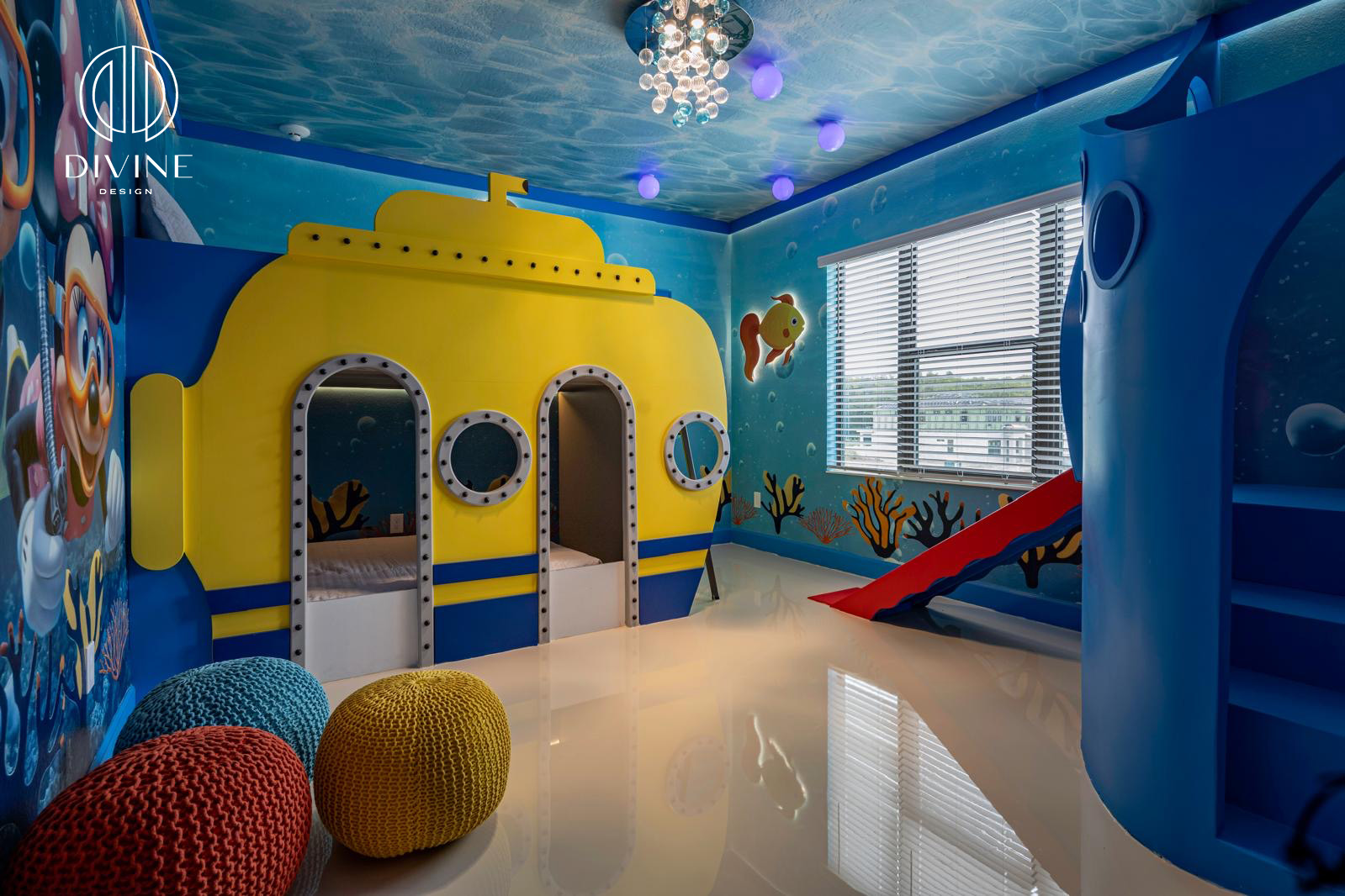 Underwater-themed kids room with yellow submarine bed, blue slide, murals, and knit poufs.