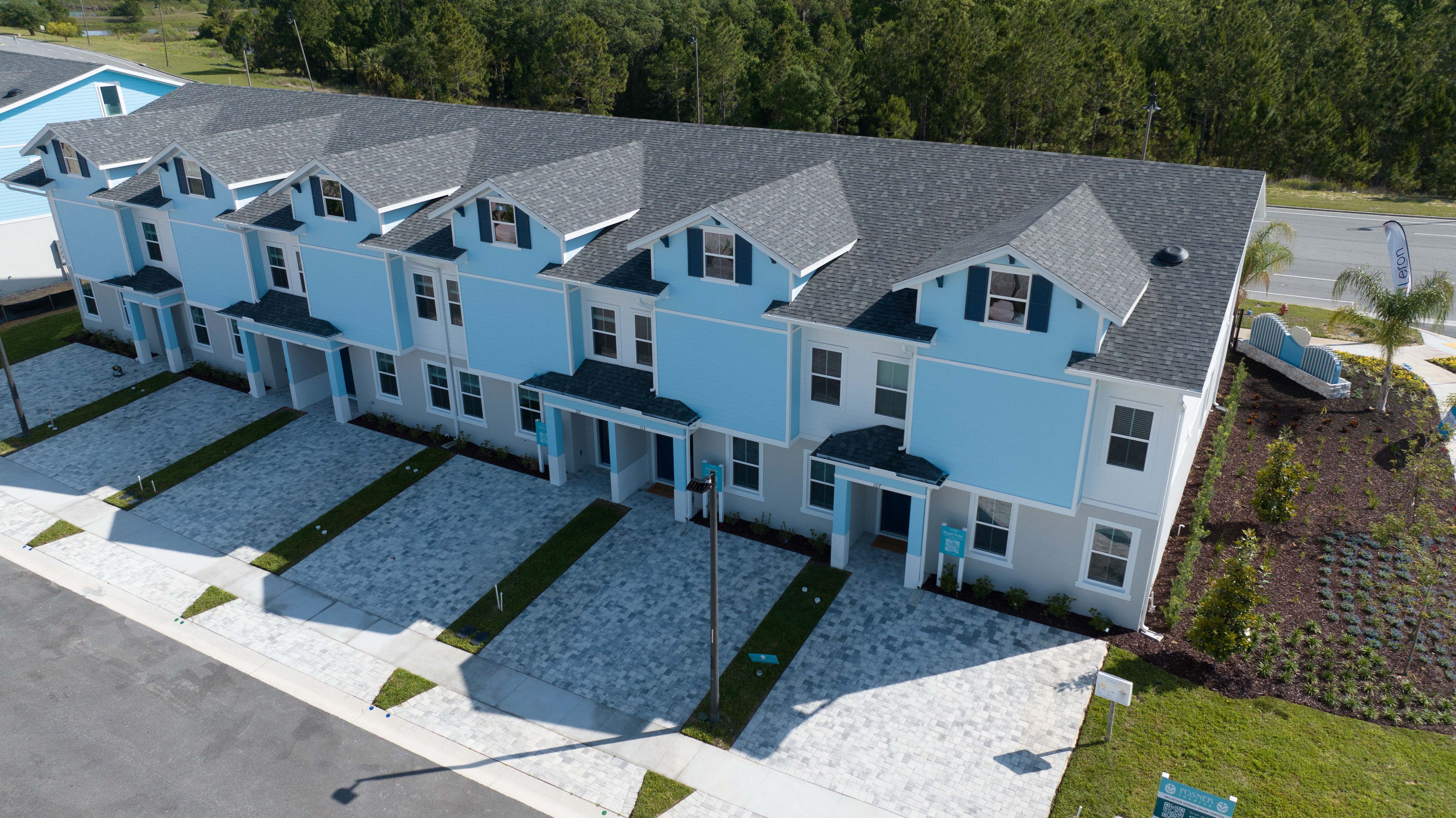 Row of blue and white townhomes with paved driveways and landscaped yards.