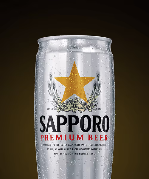 Silver can of Sapporo Premium Beer with condensation droplets against a dark background.