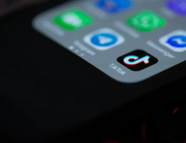 Close up of smartphone featuring the TikTok app icon among other blurred app icons.