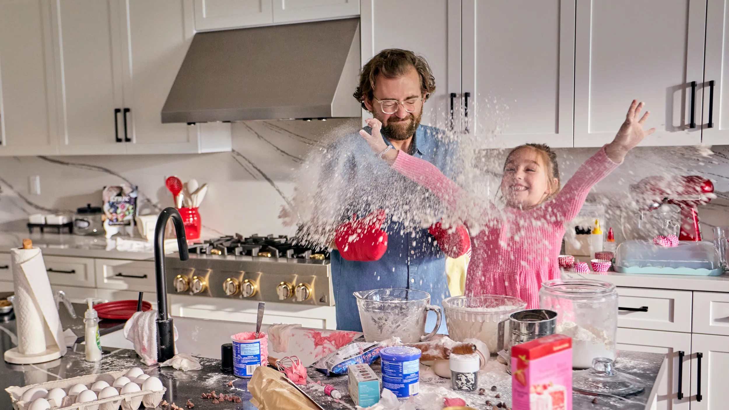 Father and daughter baking in a messy kitchen, flour flying as they laugh and enjoy the fun of cooking together.