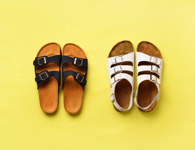 Two pairs of cork-footbed sandals, one black and one white, arranged side by side on a bright yellow background.