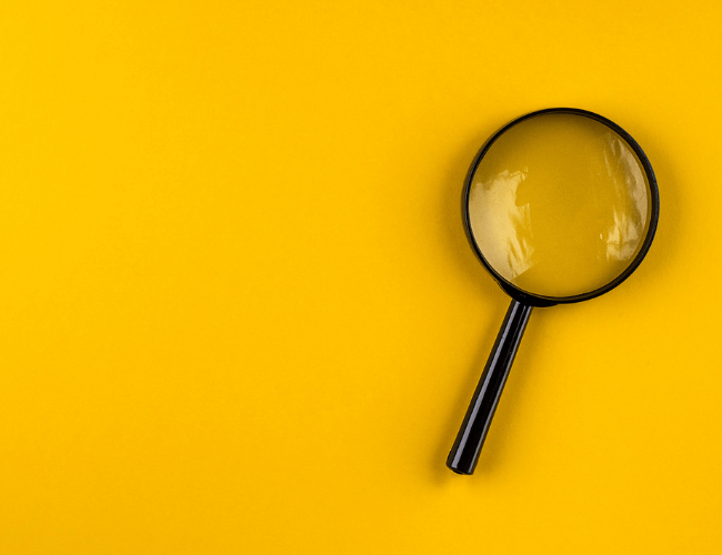Large black magnifying glass placed on a bright yellow background.