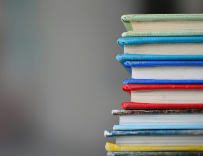 Extra closeup of colorful college textbooks stacked on top of eachother.