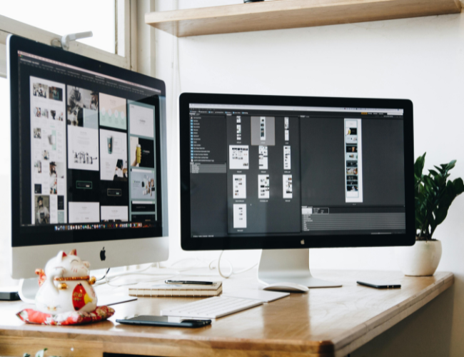Desktop computer monitors on desk display website wireframes and detailed templates.