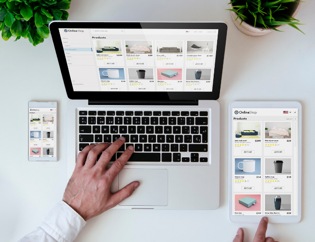 Hands using a laptop displaying an ecommerce product page with a smartphone and tablet showing the same site nearby.