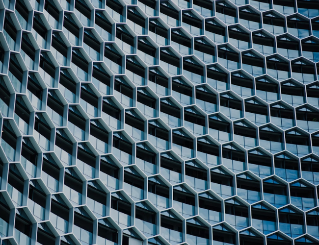 Repeating geometric pattern of dark blue office building windows in a high-rise facade.
