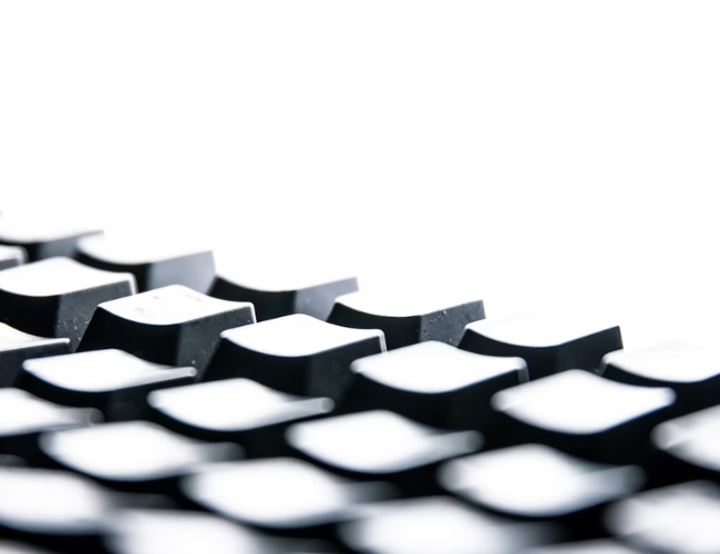 Low-angle close-up of a black computer keyboard's keys against a white background.