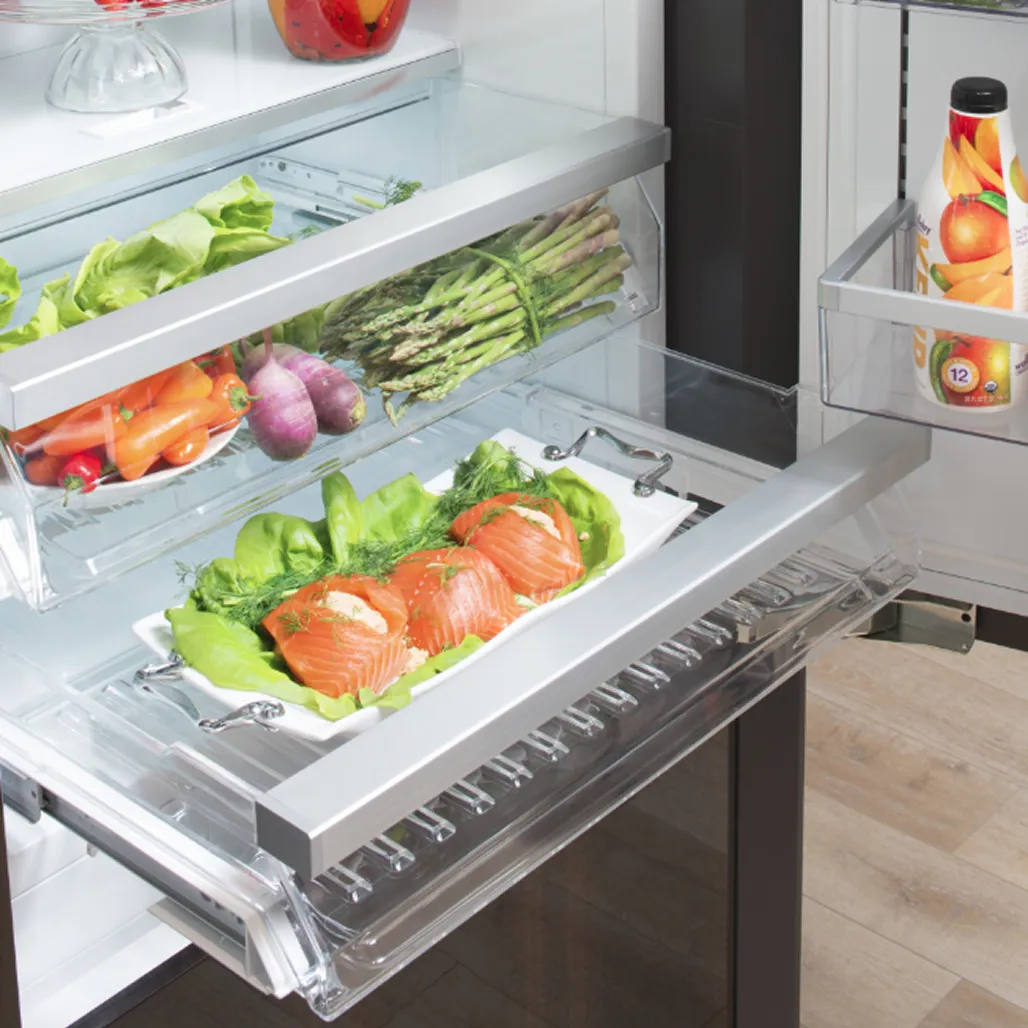 Close-up of an open Bosch refrigerator drawer showcasing a fresh salmon fillet on a bed of lettuce, with asparagus, vegetables, and condiments visible on the shelves above.