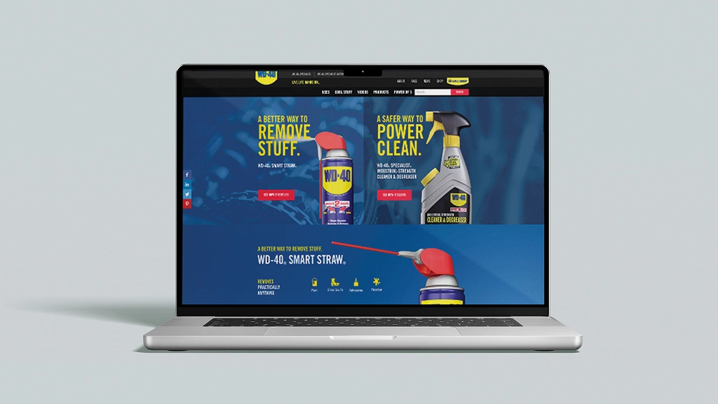 An open laptop displays the WD-40 website, featuring product images with blue and red accents. Text reads "Remove Stuff" and "Power Clean."