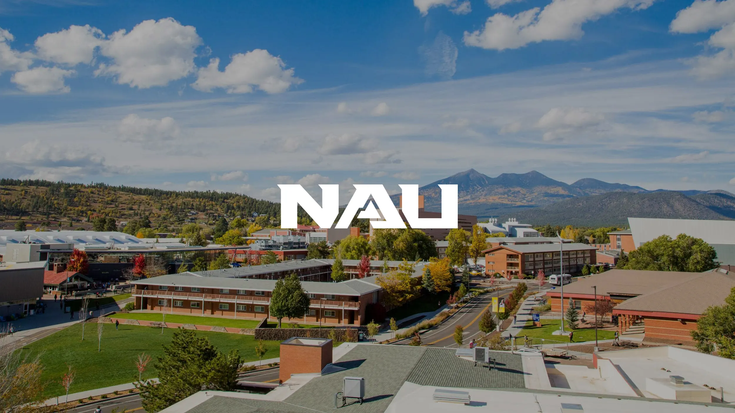 Aerial view of Northern Arizona University's campus with mountain backdrop and fall foliage, with the NAU logo overlaid in white.
