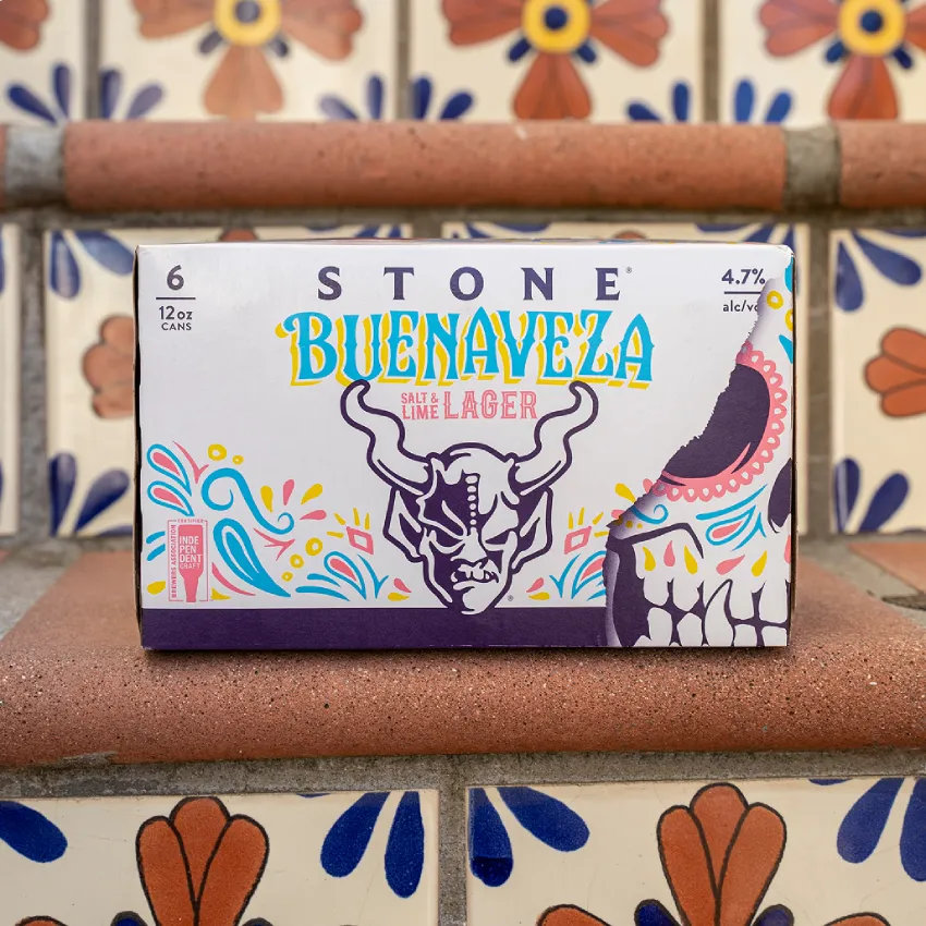 A Stone Buenaveza Salt & Lime Lager 6-pack resting on colorful Spanish tile steps.