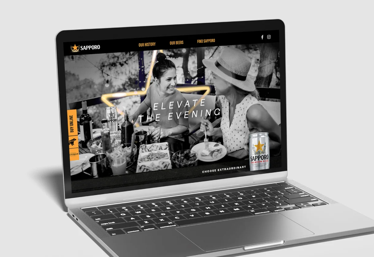 Laptop displaying Sapporo beer website. Two women enjoy a meal with drinks, smiling. Text reads “Elevate the Evening” with a relaxed, social vibe.