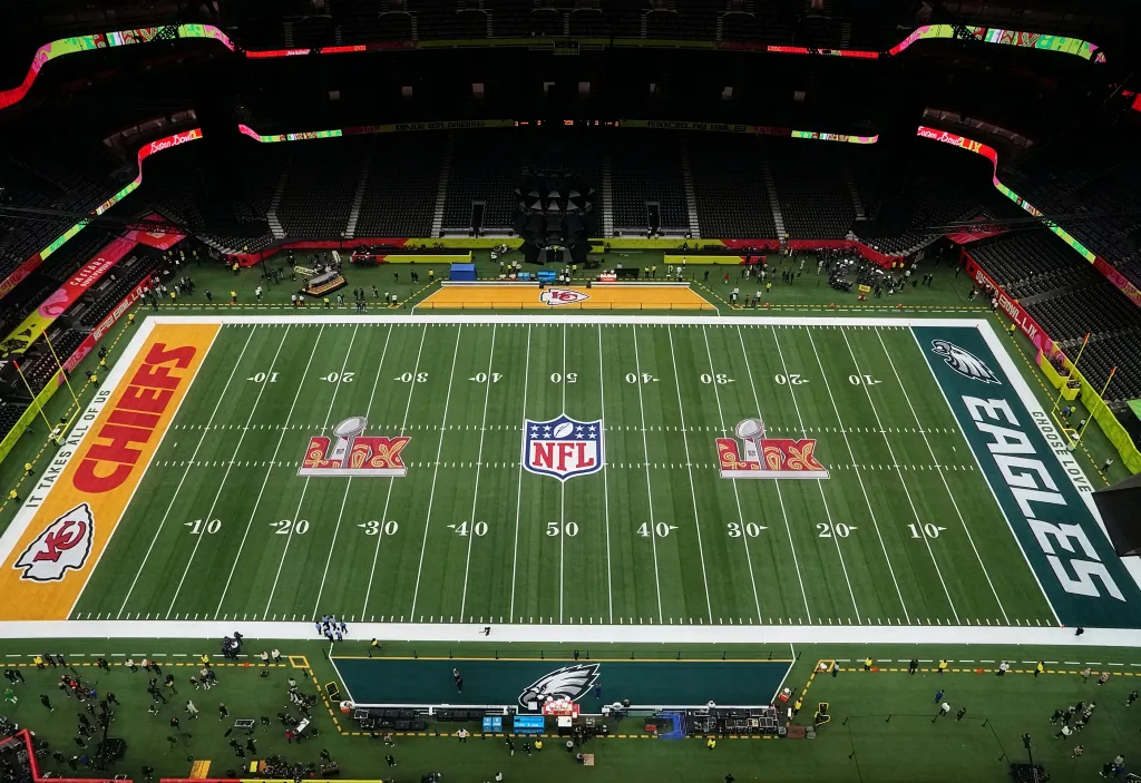 Aerial view of an NFL field set for a game between the Chiefs and Eagles, with team logos painted on the field.
