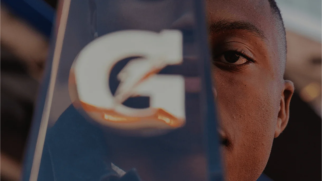 Close-up of a person partially obscured by a translucent Gatorade logo. The tone is thoughtful, highlighting focus and determination.