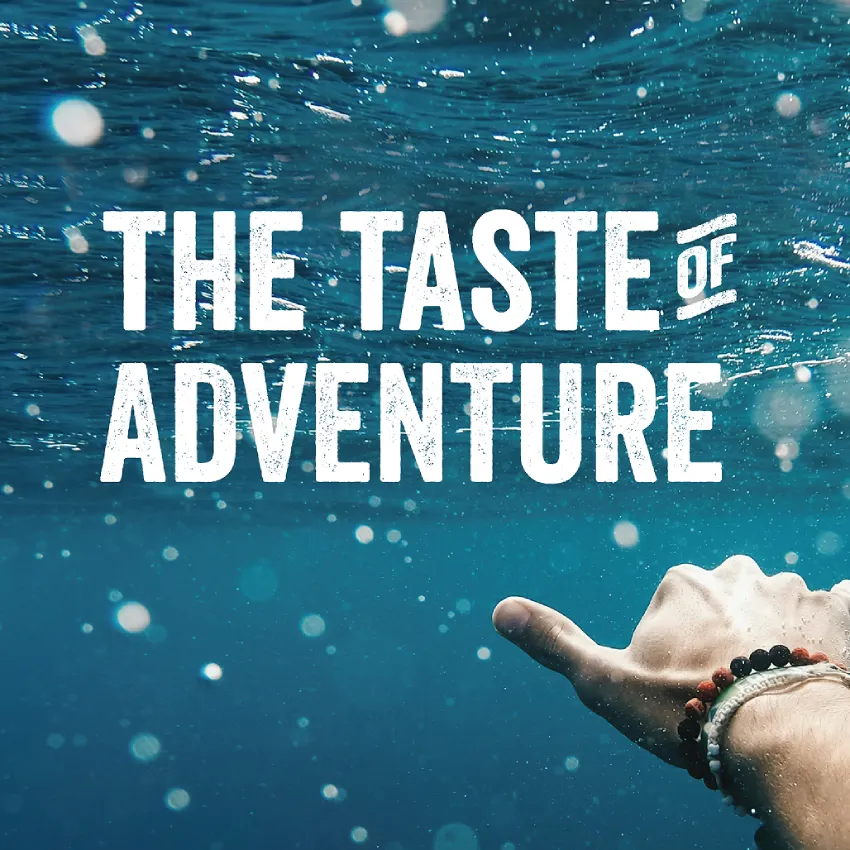  "The Taste of Adventure" headline over an underwater shot of a hand reaching toward the surface in clear blue water.