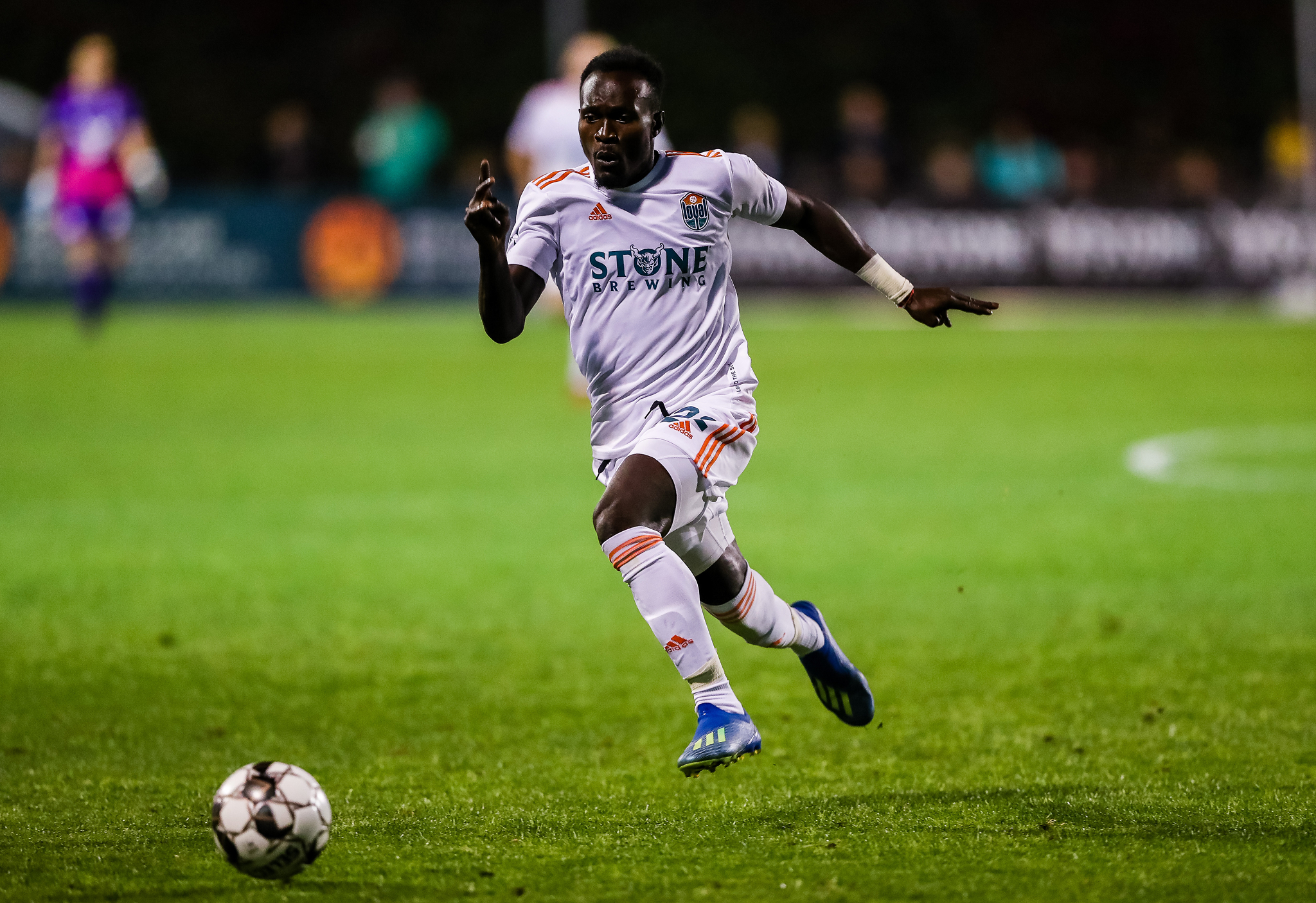 SD Loyal midfielder in Stone Brewing-sponsored kit chasing down the ball during a match. 