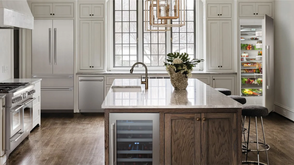Luxury white kitchen with Thermador built-in column refrigerator, French door fridge, pro range, wine cooler in island, and tall arched windows.