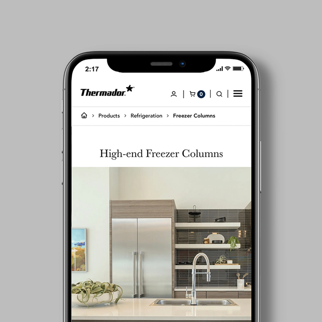 Smartphone showing the Thermador mobile site's High-end Freezer Columns page with a stainless built-in column in a modern kitchen.