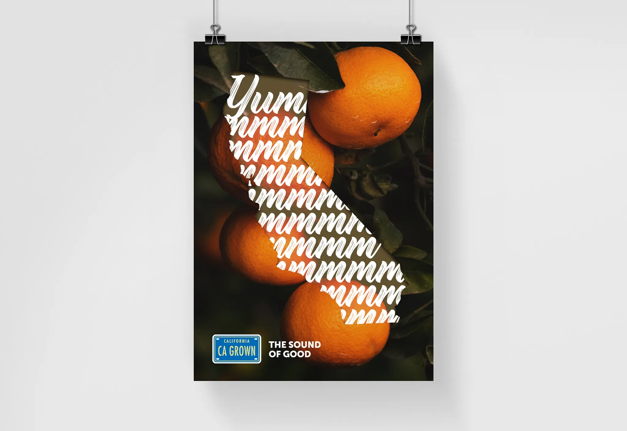 Poster featuring vibrant oranges against dark leaves, shaped like California with the word "Yummmm" in white. "CA GROWN" label and "The Sound of Good" text.