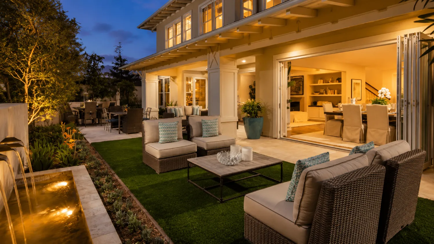 Shea Homes outdoor living space at dusk with fire feature, lounge seating, and open patio doors to bright interior