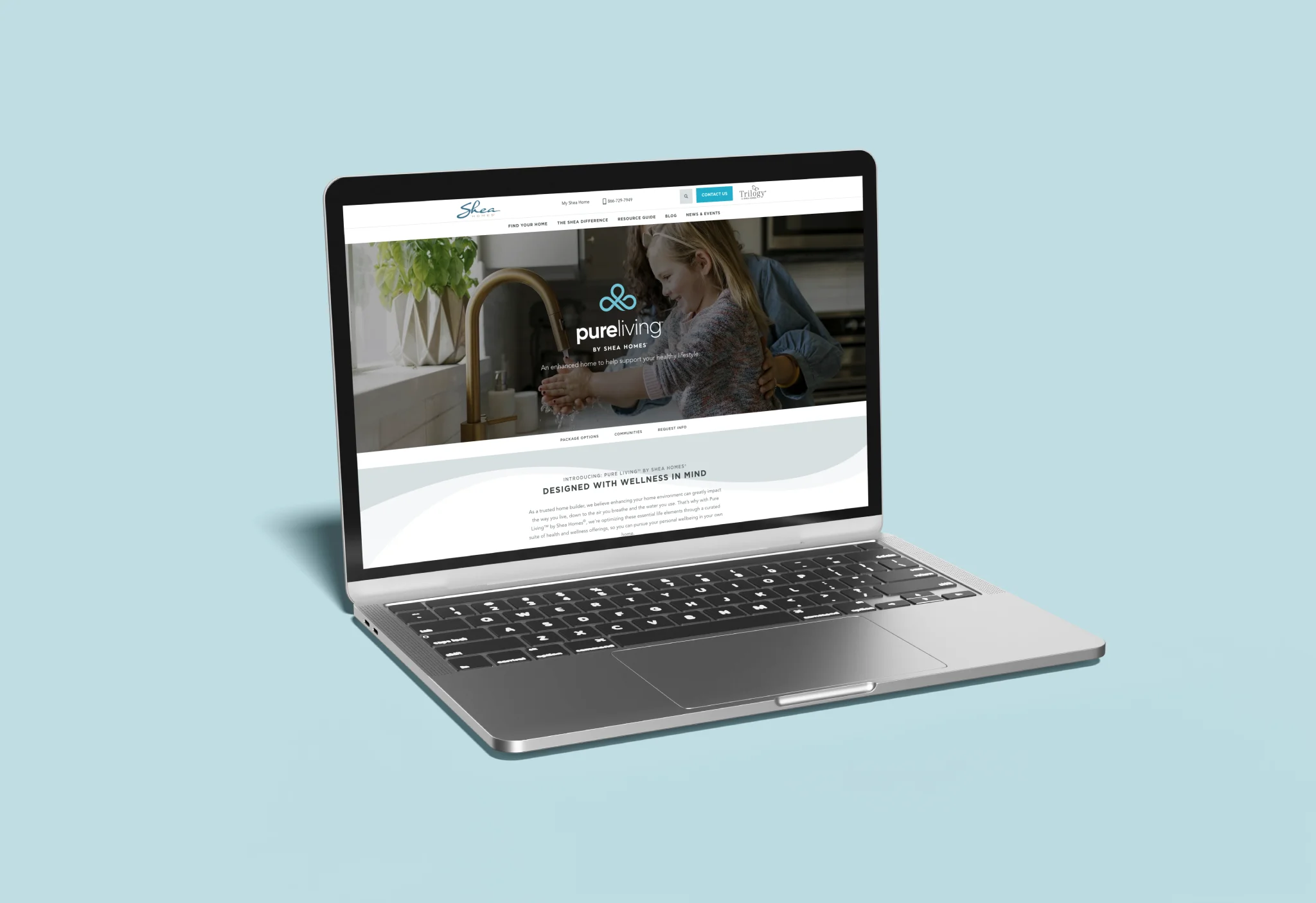 Laptop displaying Shea Homes Pure Living webpage with "Designed with Wellness in Mind" section