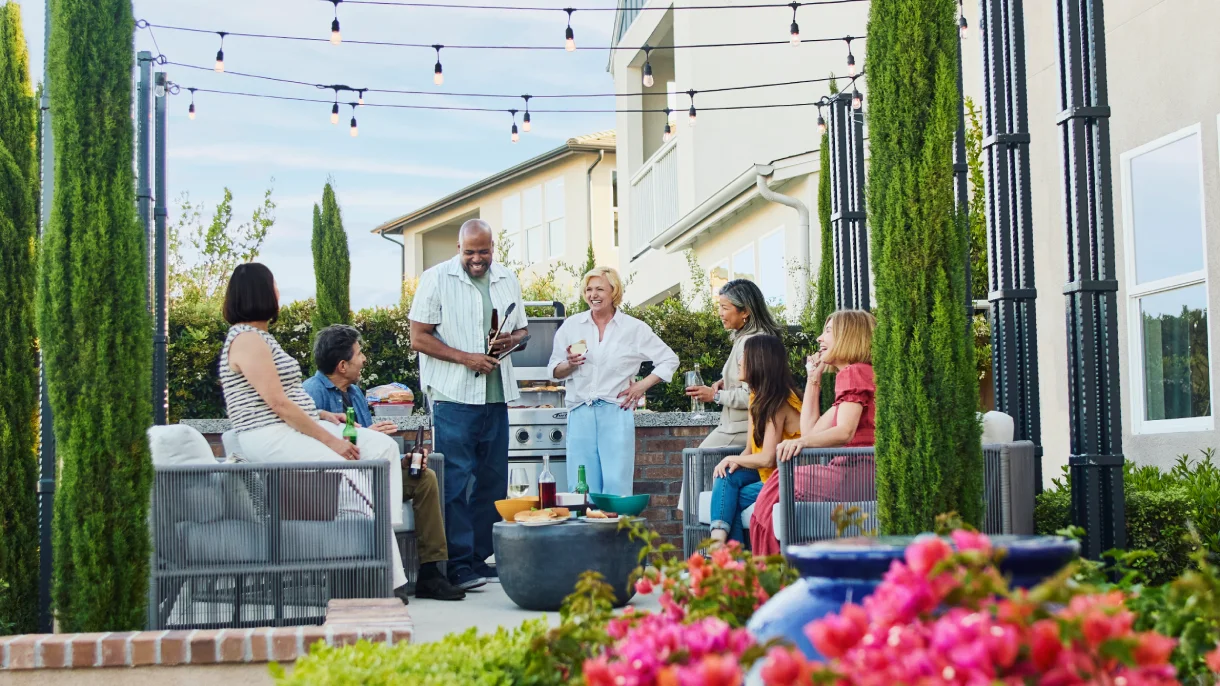 Multigenerational group enjoying an outdoor evening gathering with string lights on a Shea Homes patio