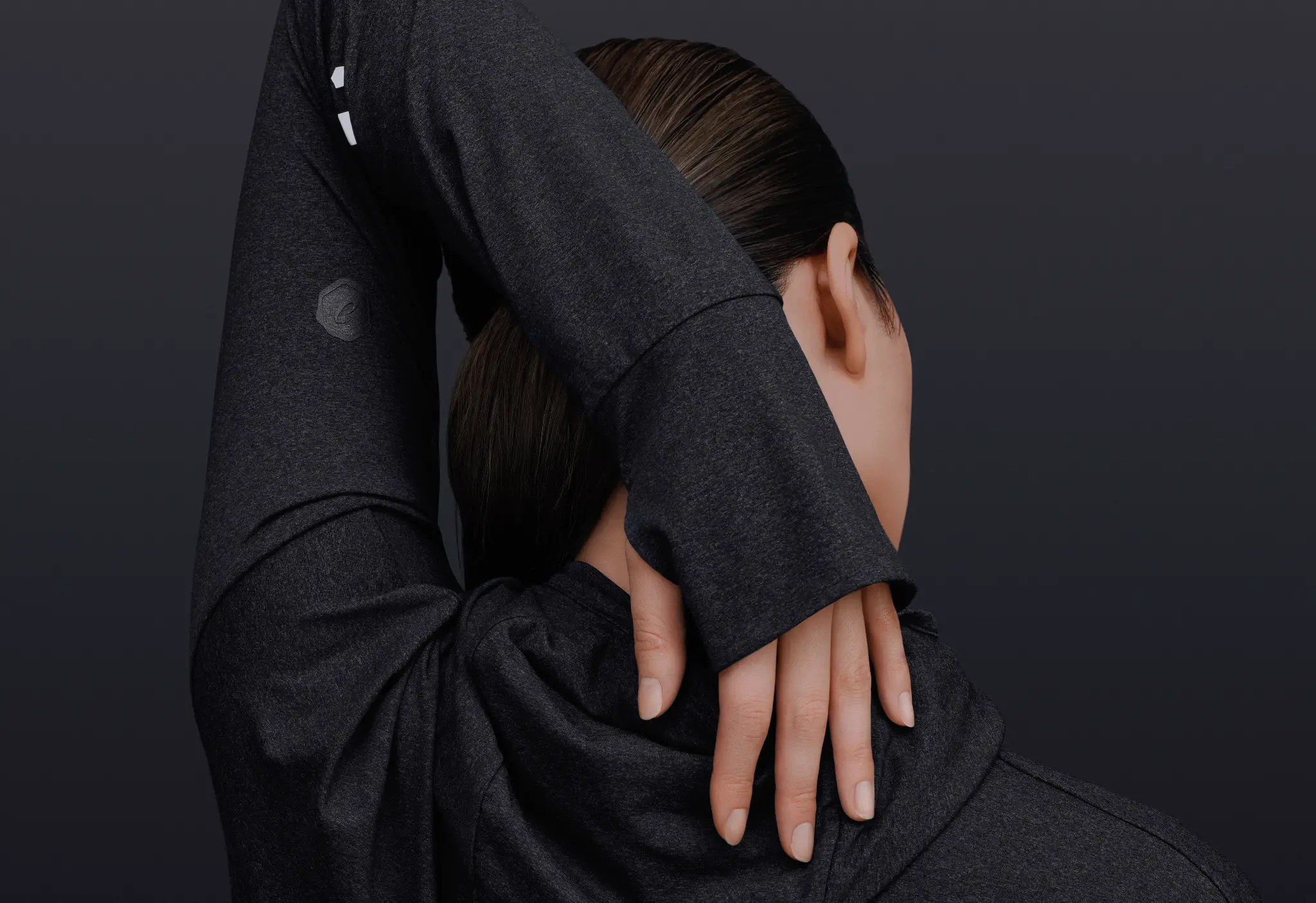 Model stretching an arm behind the head in a dark heathered ASICS JYUNI Black Collection long-sleeve top