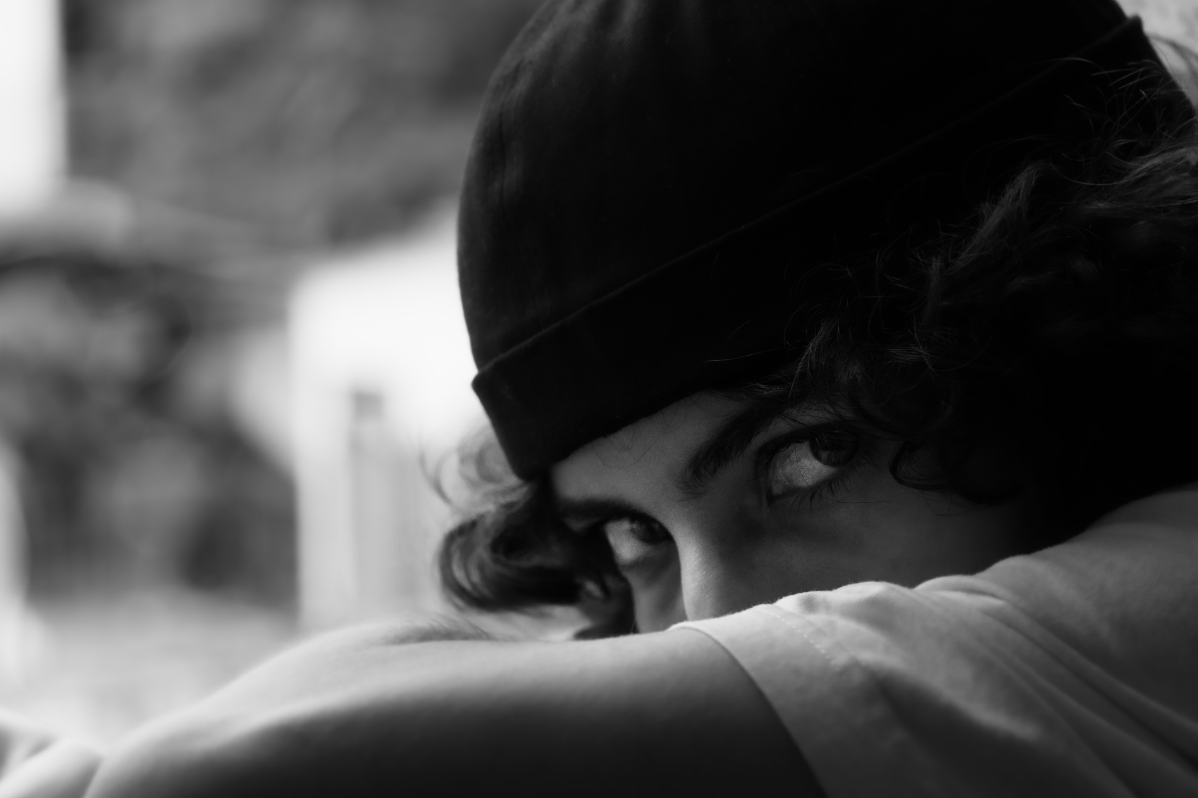 black and white photo of the photographer’s face, with an arm covering the mouth and letting highlight the eyes of this