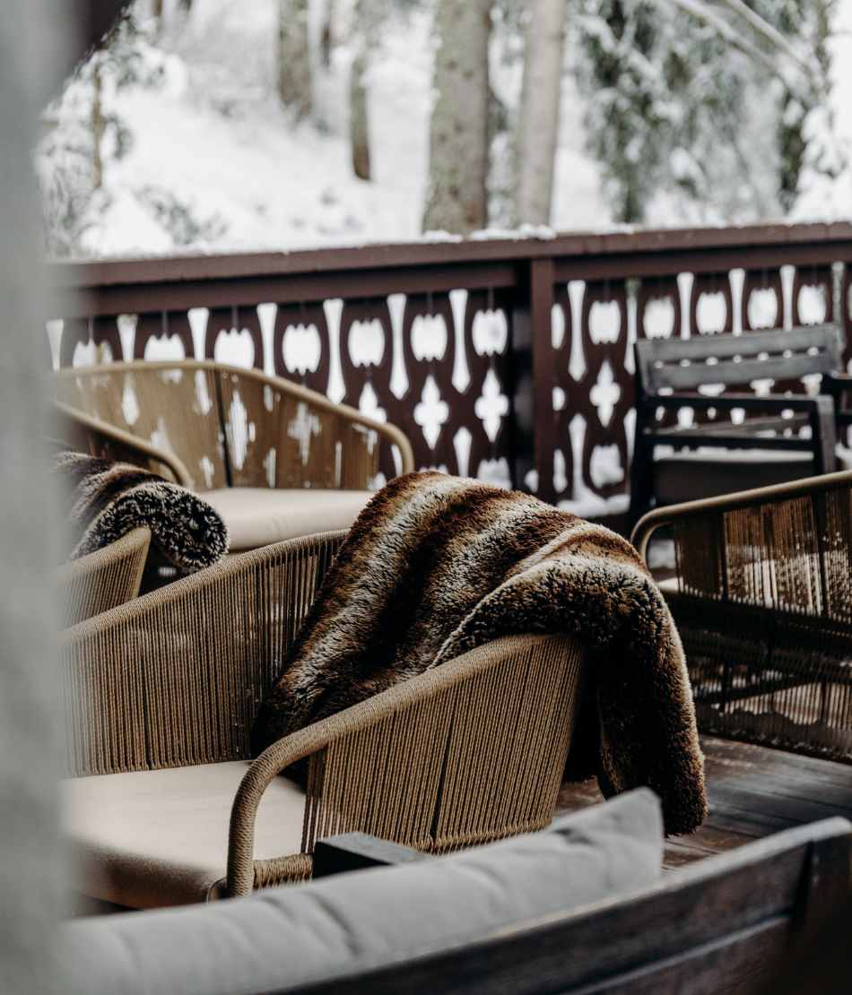 Terrasse enneigée avec fauteuils et plaids au cœur des Chalets du Mont d’Arbois — Megève.
