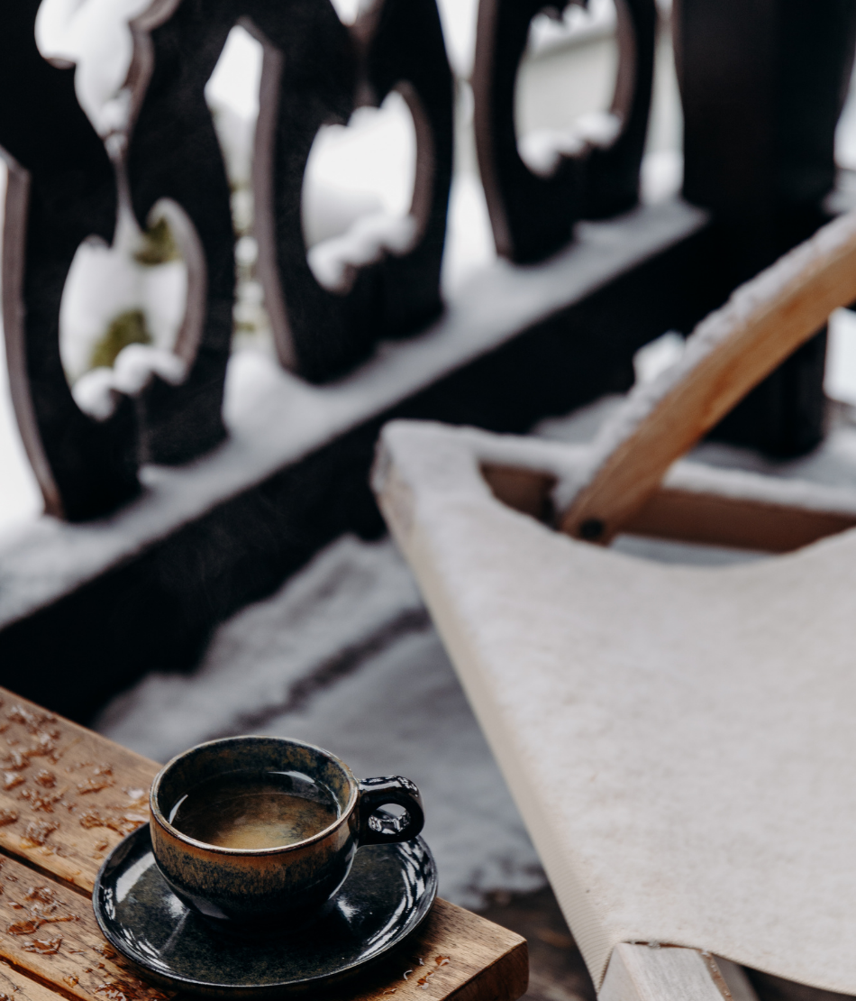 Pause café sur une terrasse enneigée des Chalets du Mont d’Arbois — Megève.