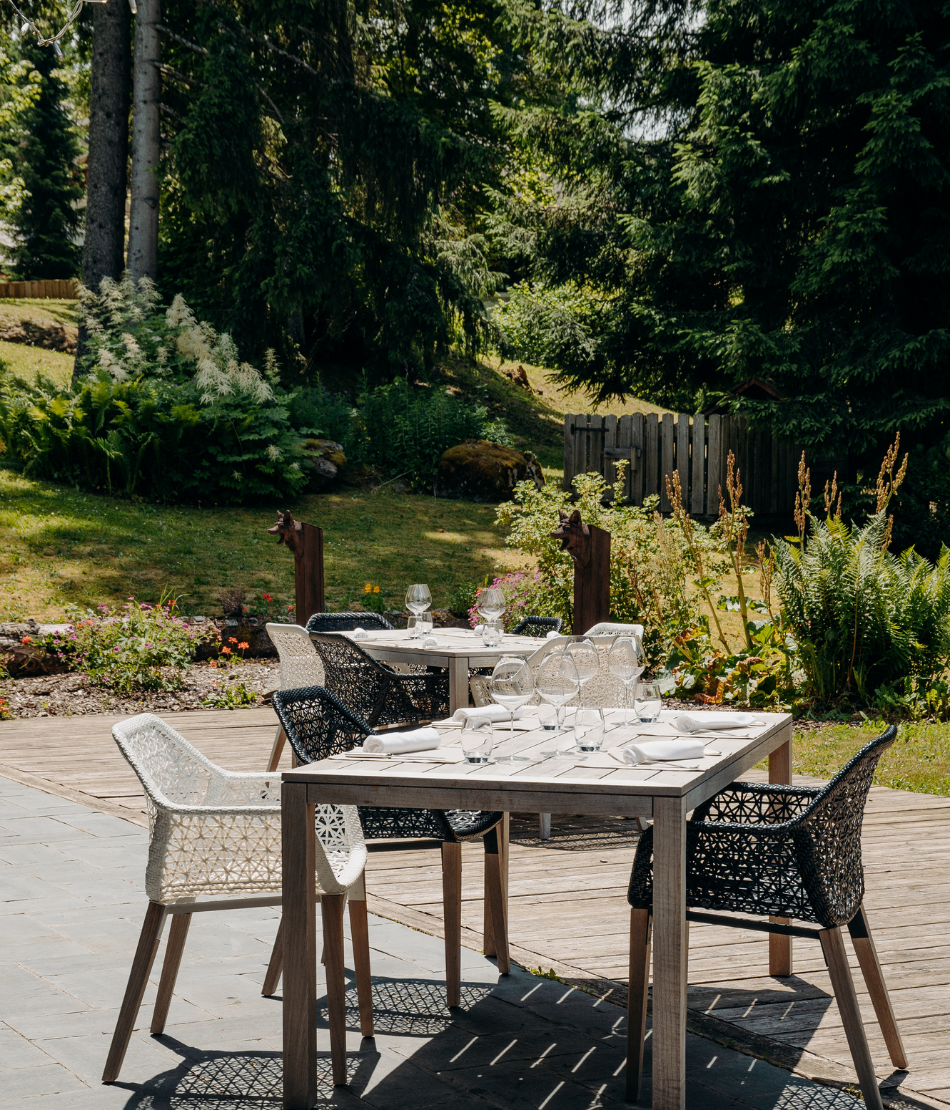 Tables dressées sur la terrasse du restaurant au cœur des jardins des Chalets du Mont d’Arbois — Megève.
