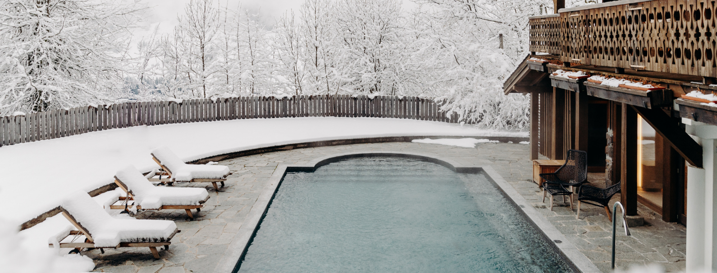 Piscine extérieure chauffée entourée de neige aux Chalets du Mont d’Arbois — Megève.