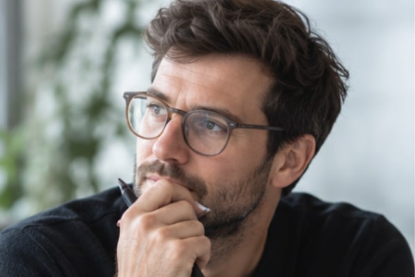 A man with glasses is thinking. 