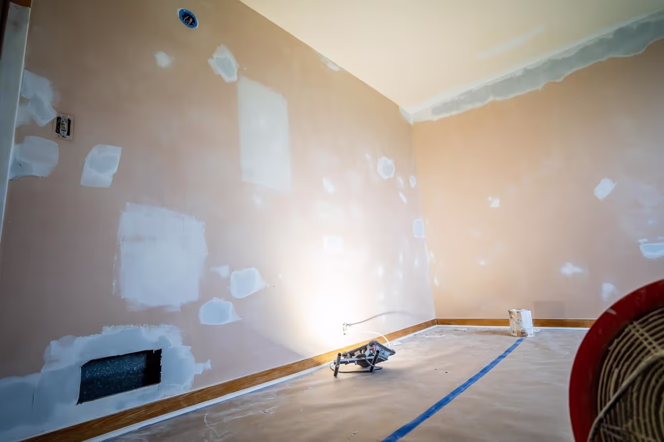 Drywall repair in progress on an interior wall of a Michigan home before painting, showing joint compound being applied to a patched section