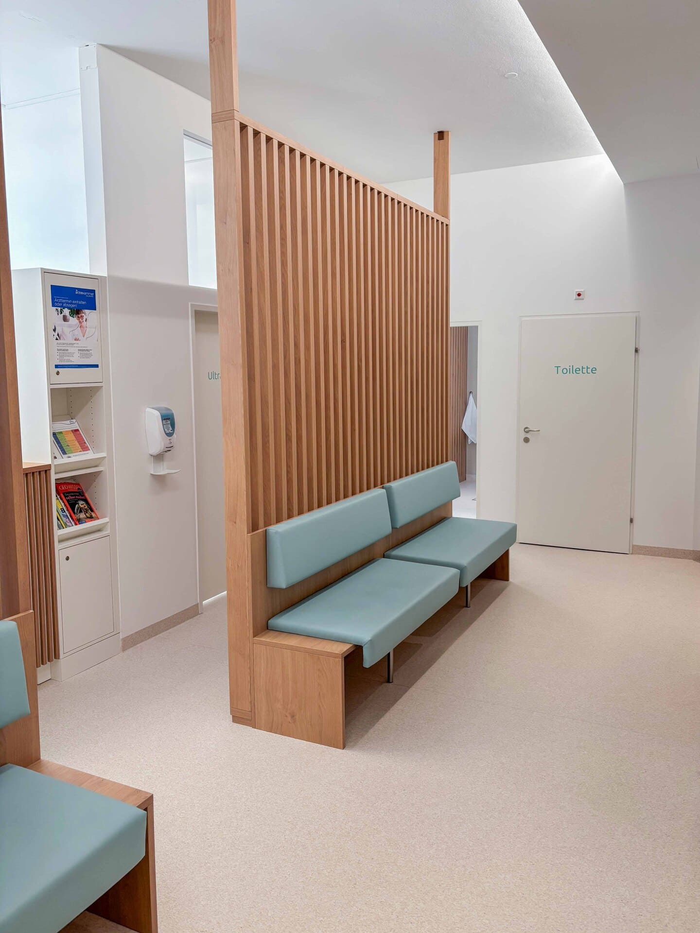 Wartebereich der Ordination Dr. Köllerer in Salzburg mit Sitzbänken und raumgliedernden Holzlamellen